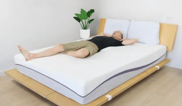 A tall Man lying on a Purple Mattress demonstrating its durability.