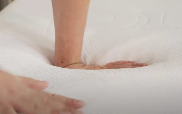 Person pressing both hands on the Purple mattress grid layer, demonstrating the feel of the material.