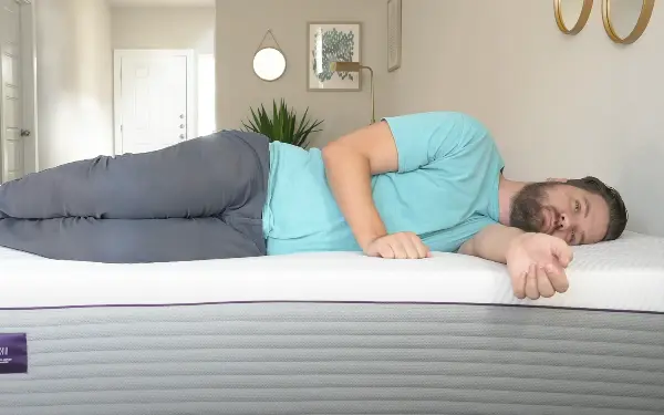 Heavy person lying on their side on a Purple mattress, illustrating the mattress's support and comfort for heavier individuals.