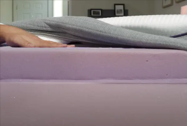 Close-up view of the layers of a Purple mattress with the cover lifted, showing the thickness and construction suitable for heavier individuals.