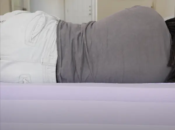 Person lying on their side on a Purple Mattress, demonstrating the mattress' ability to conform to the body's natural curves.